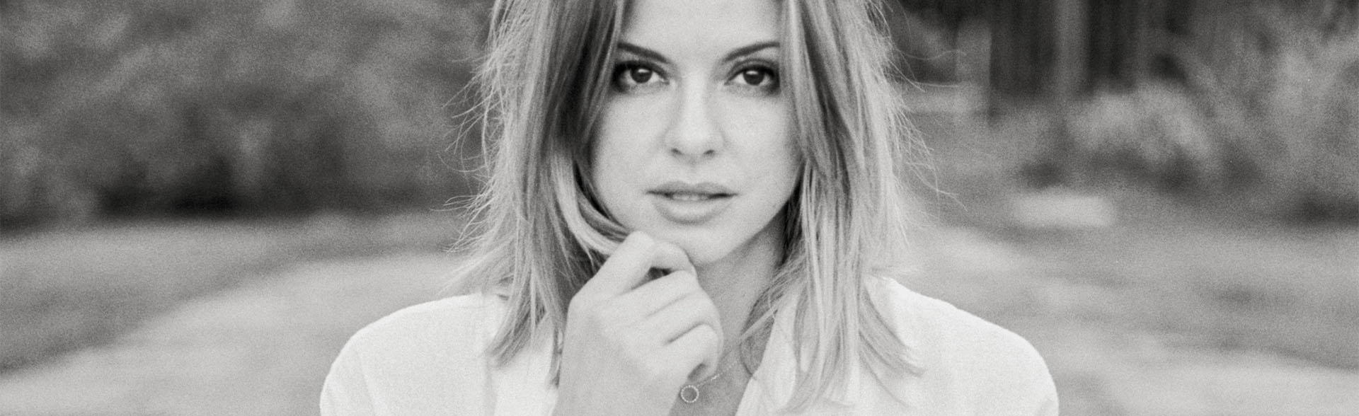 Schwarz-Weiß-Porträt einer Frau, die ihre Hand ans Kinn hält.